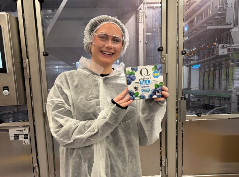 Lisa står i meieriet og holder opp Q Yoghurt UTEN, blåbær 4-pakning